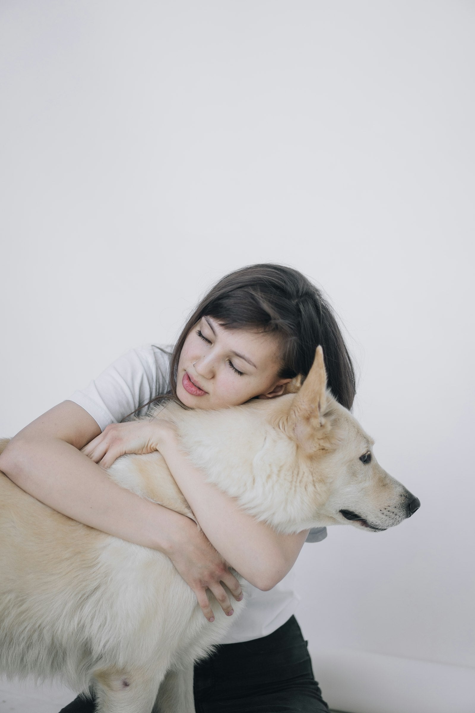 Woman hugging her white dog at home